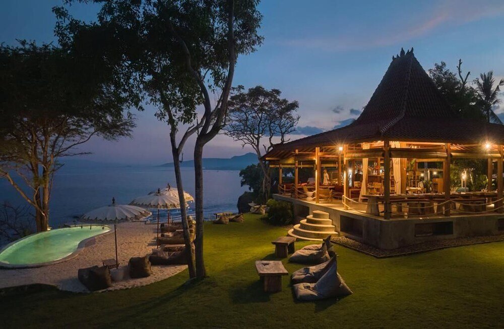 Curved infinity pool with ocean views at Bali Cliff Glamping