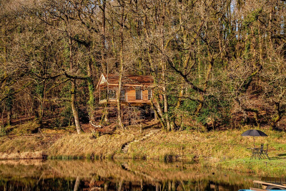 Balcón de la casa del árbol con vistas a los árboles y al lago en Devon